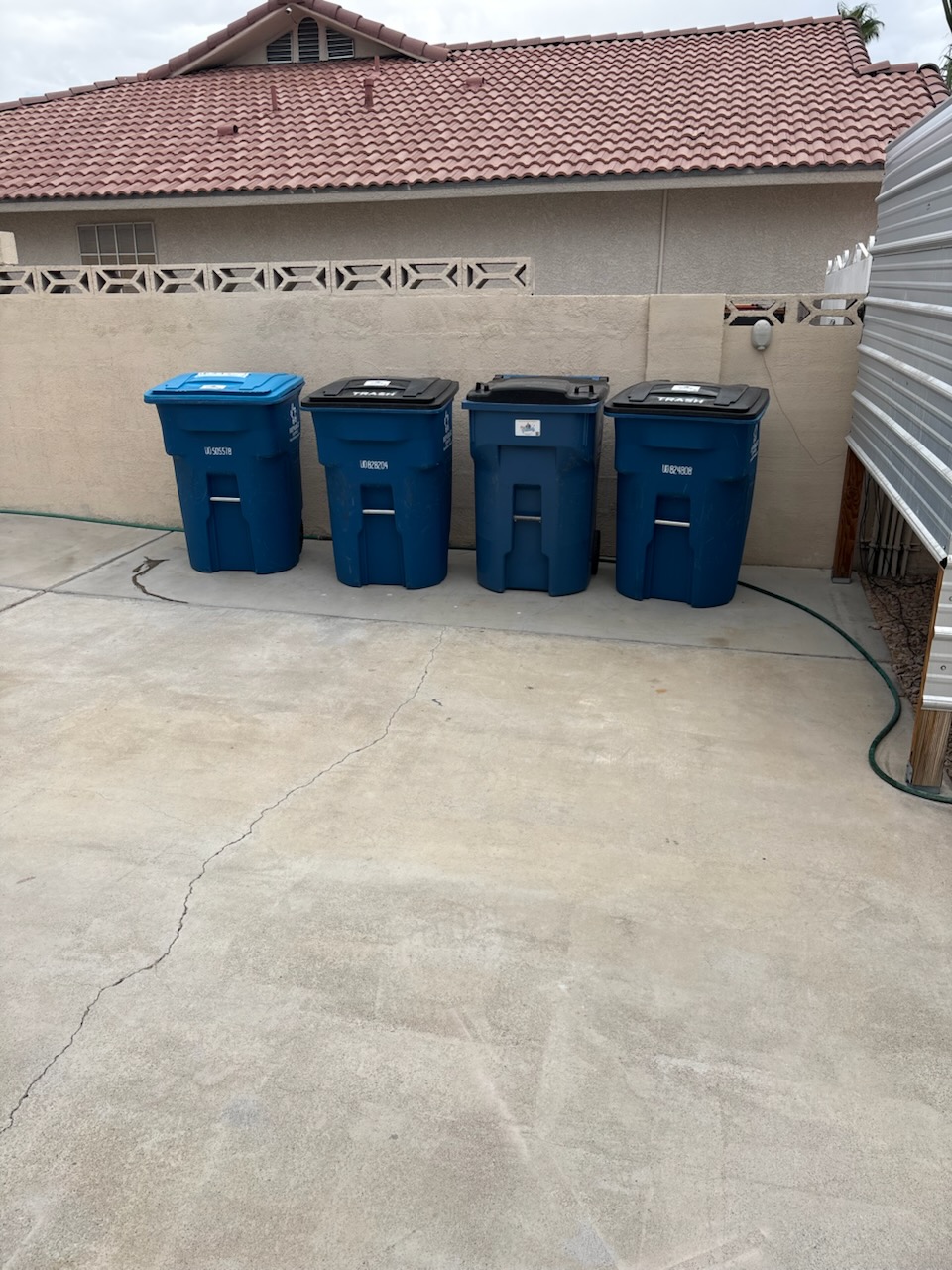 Four residential trash and recycling bins stored neatly beside a Las Vegas home