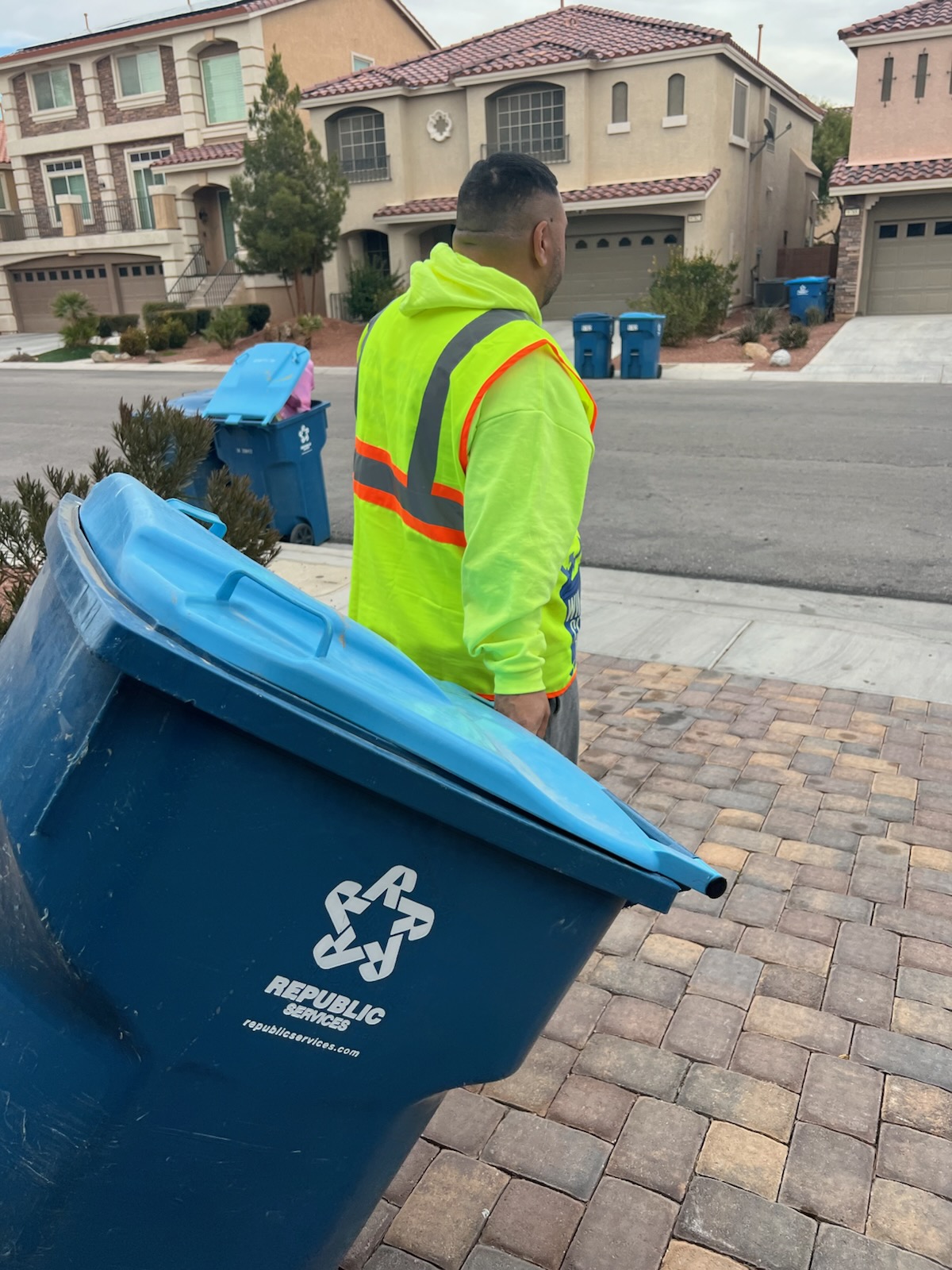 Win City Bins crew member rolling a residential trash bin toward the curb